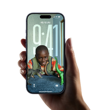 잠금 화면의 이미지에 맞게 시간의 형태가 동적으로 변하는 새로운 Liquid Glass 디자인을 보여주는 iPhone 기기를 들고 있는 손