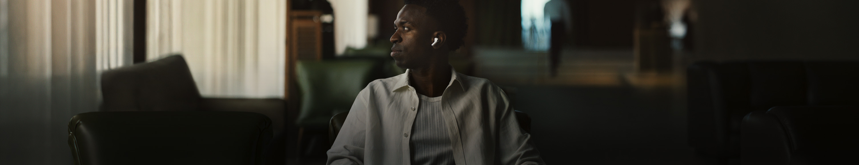 Person in weißem Hemd, den Kopf zur Seite gedreht, linker AirPods Pro 3 In-Ear Kopfhörer sichtbar