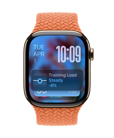 Apple Watch i rosaguld med en flettet rem i farven mandarin. Urskiven viser datoen øverst til venstre, tidspunktet med tal øverst til højre, Træningsbelastning-widget nederst, alt i gennemsigtigt Liquid Glass
