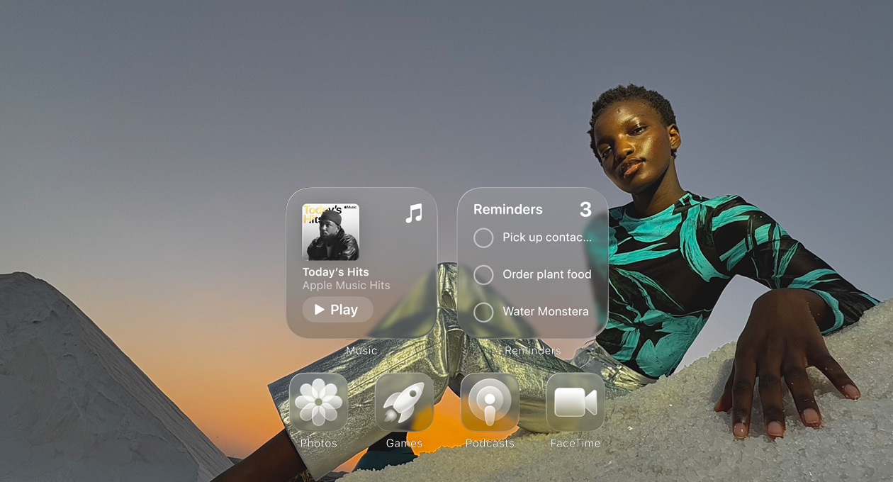 Layar Liquid Glass dengan ikon aplikasi yang jernih, seperti Apple Music, Pengingat, Foto, Game, Podcast, dan FaceTime yang membias di depan wallpaper